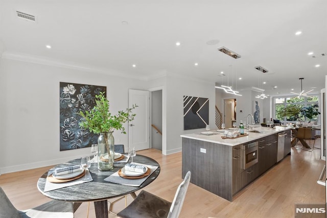 kitchen featuring dark brown cabinets, a spacious island, dishwasher, and light hardwood / wood-style flooring