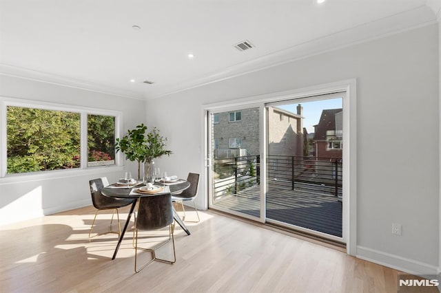 dining space featuring light wood-type flooring, a wealth of natural light, and ornamental molding