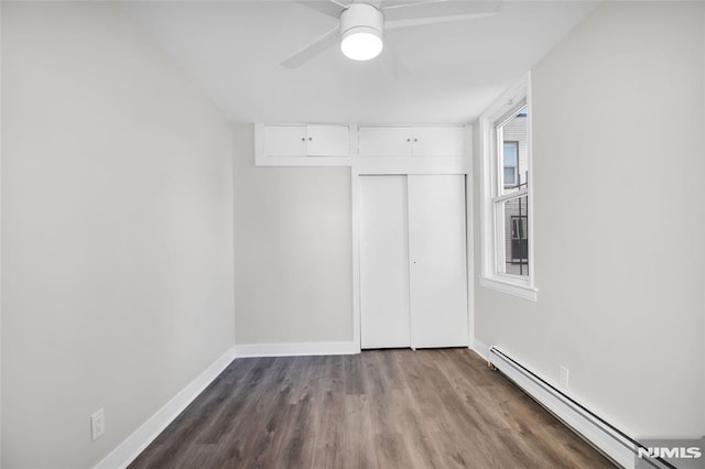 unfurnished bedroom featuring multiple windows, ceiling fan, a closet, and a baseboard heating unit