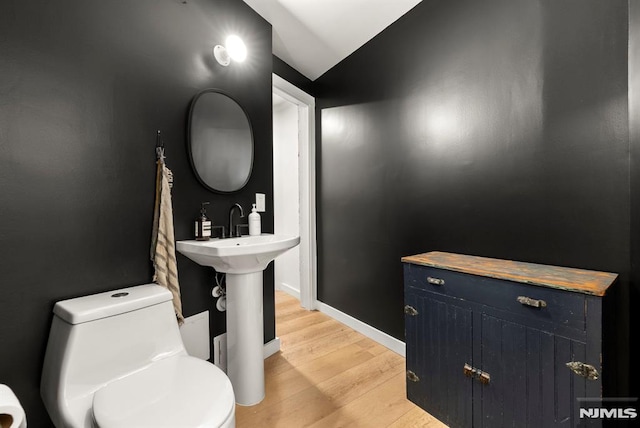 bathroom with wood-type flooring, vaulted ceiling, and toilet