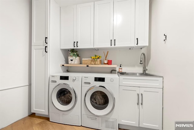 laundry room with light hardwood / wood-style flooring, cabinets, sink, and washing machine and clothes dryer