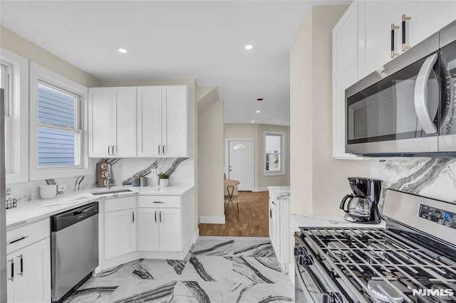 kitchen featuring white cabinets, sink, light stone countertops, and stainless steel appliances