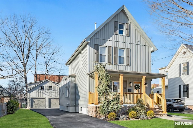 view of front of home featuring a porch, a front yard, a garage, and an outdoor structure