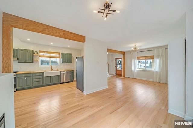 unfurnished living room with an inviting chandelier, light hardwood / wood-style floors, and sink