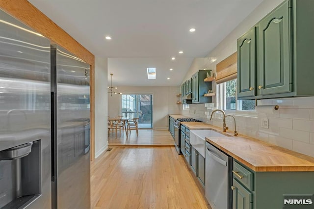 kitchen with appliances with stainless steel finishes, wooden counters, sink, and green cabinets