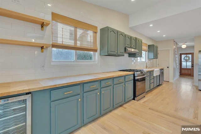 kitchen with stainless steel appliances, tasteful backsplash, light wood-type flooring, wine cooler, and wood counters