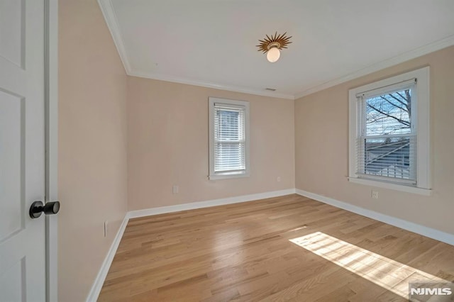 empty room featuring a healthy amount of sunlight, light hardwood / wood-style floors, and crown molding