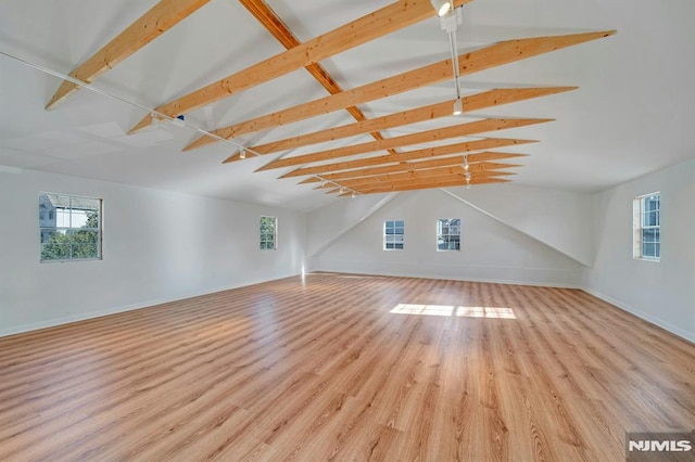 additional living space featuring light hardwood / wood-style flooring and lofted ceiling with beams