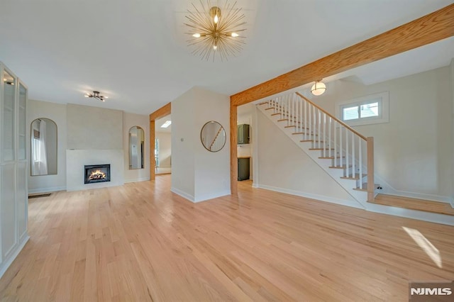 unfurnished living room featuring light hardwood / wood-style flooring and beamed ceiling