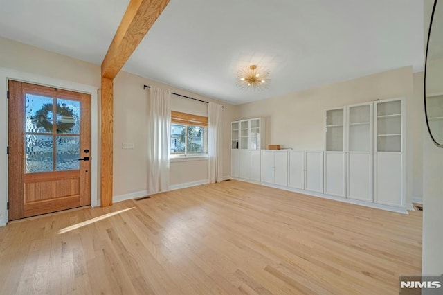 interior space featuring an inviting chandelier, light hardwood / wood-style flooring, and beamed ceiling