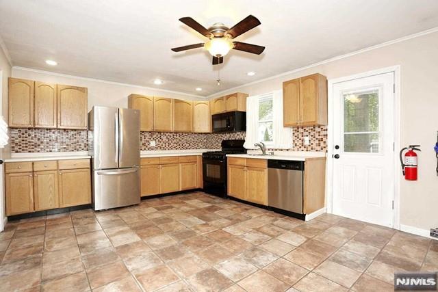 kitchen featuring light brown cabinetry, sink, ornamental molding, and black appliances