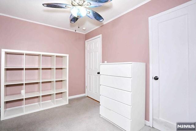 unfurnished bedroom featuring ceiling fan, crown molding, and light carpet