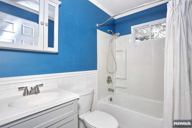 full bathroom featuring vanity, toilet, shower / bathtub combination with curtain, and crown molding