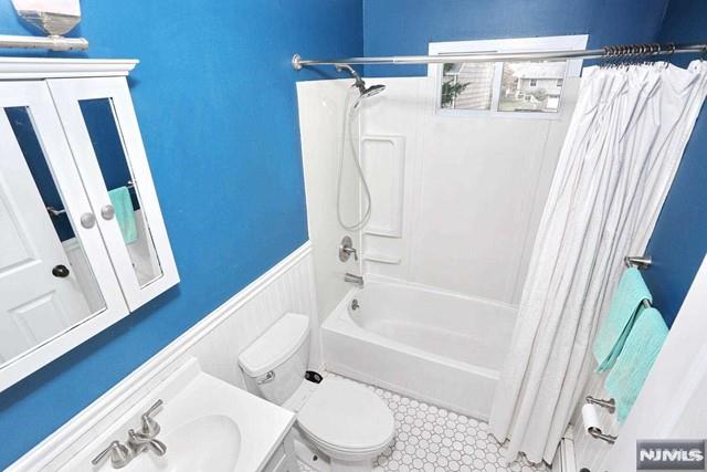 full bathroom featuring shower / tub combo with curtain, vanity, and toilet