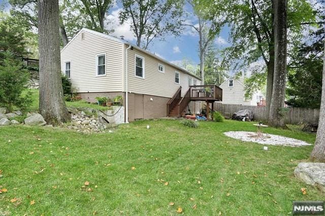 back of property featuring a wooden deck and a lawn