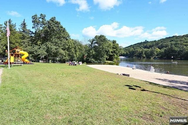 exterior space with a playground, a water view, and a lawn