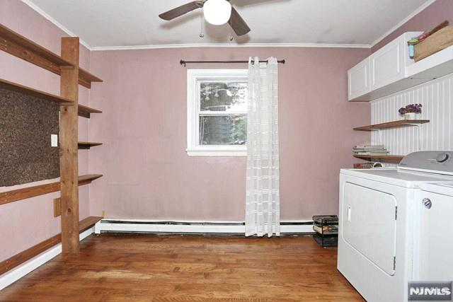 clothes washing area with dark wood-type flooring, separate washer and dryer, ceiling fan, and crown molding