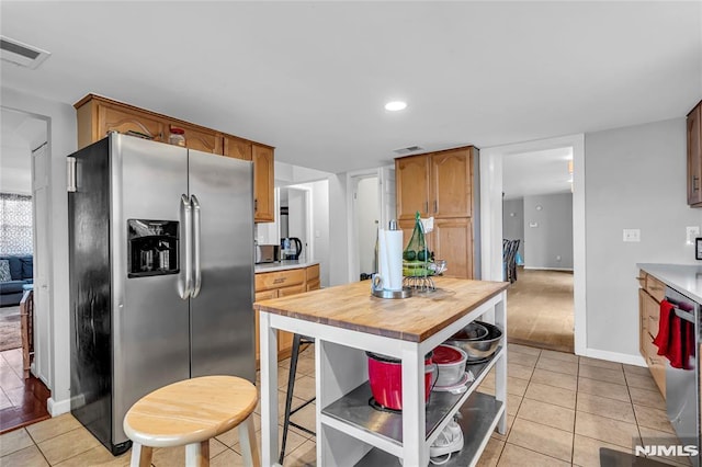 kitchen featuring appliances with stainless steel finishes, butcher block counters, and light tile patterned flooring