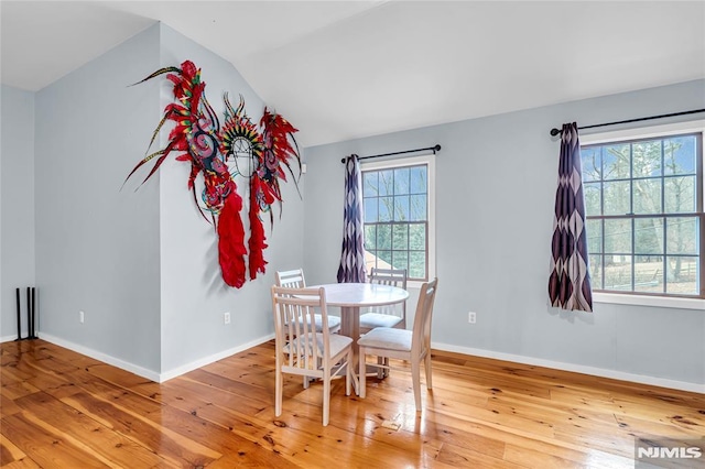 dining room with hardwood / wood-style floors and vaulted ceiling