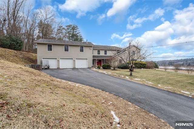 view of front of property with a garage, a front yard, and cooling unit