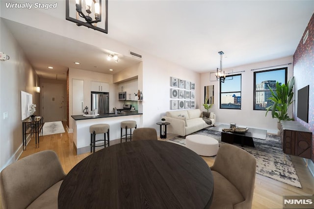 dining space featuring light wood-type flooring and a notable chandelier