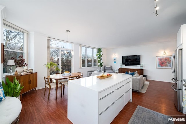 kitchen with white cabinets, pendant lighting, a kitchen island, and stainless steel refrigerator