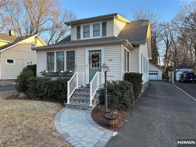 bungalow-style home with a garage and an outbuilding