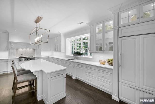 kitchen with white cabinets, decorative light fixtures, a kitchen island, and tasteful backsplash