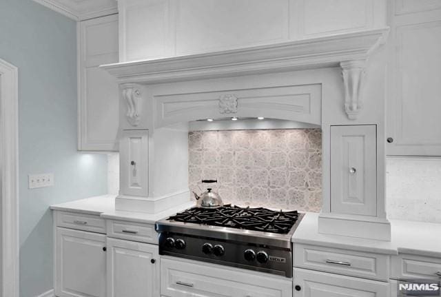 kitchen with tasteful backsplash, white cabinetry, ornamental molding, and stainless steel gas stovetop