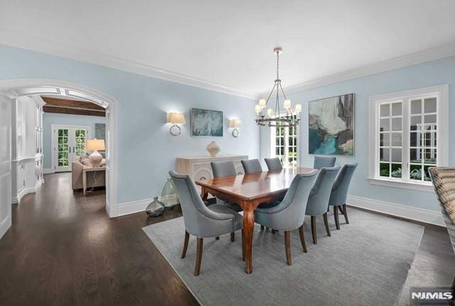 dining area with crown molding, french doors, dark wood-type flooring, and an inviting chandelier