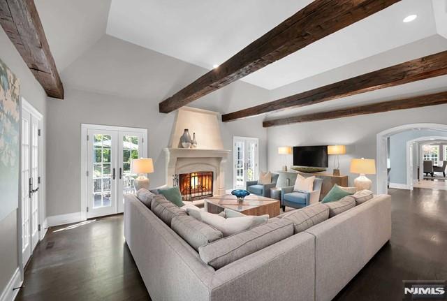 living room with a fireplace, french doors, and beamed ceiling