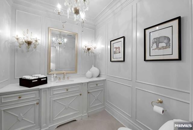 bathroom with ornamental molding, vanity, a chandelier, and toilet