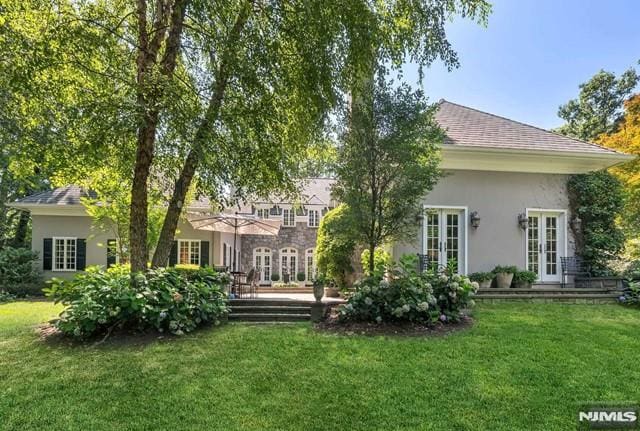 rear view of property featuring a lawn and french doors