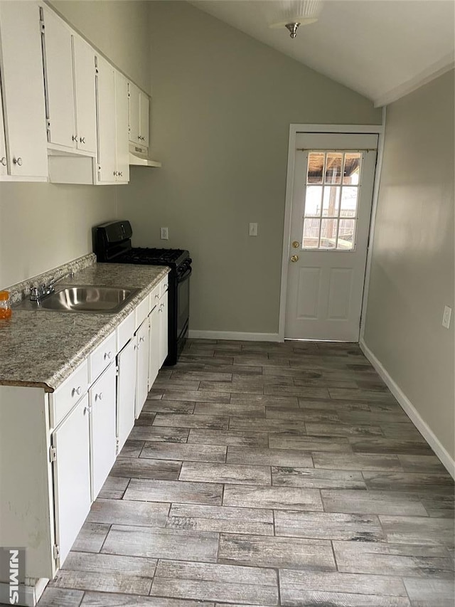 kitchen with black gas range, lofted ceiling, white cabinets, sink, and hardwood / wood-style flooring