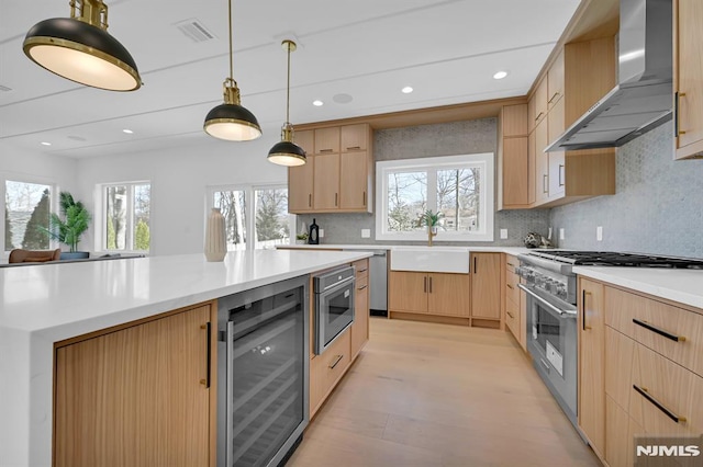 kitchen featuring light brown cabinets, wall chimney exhaust hood, sink, wine cooler, and stainless steel stove