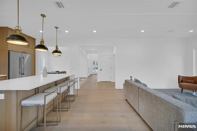 kitchen featuring a kitchen bar, light wood-type flooring, hanging light fixtures, and high quality fridge