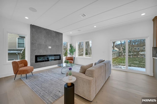 living room with a tile fireplace and light hardwood / wood-style flooring