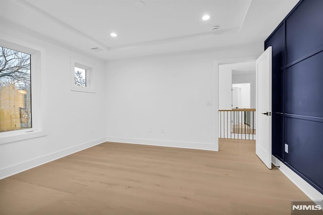 unfurnished room with hardwood / wood-style floors and a tray ceiling