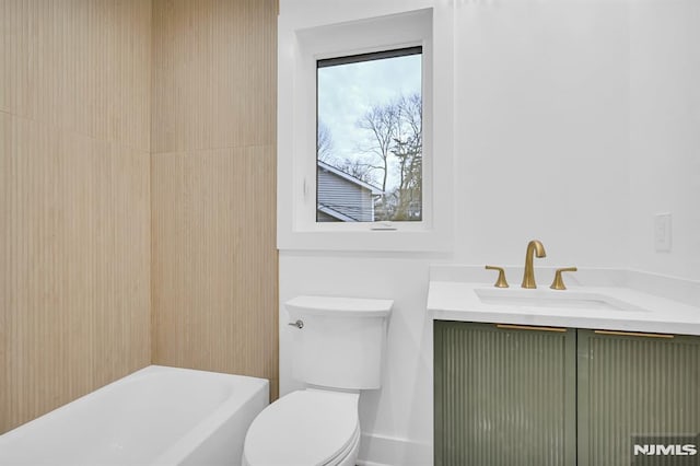 bathroom with a bathtub, vanity, and toilet