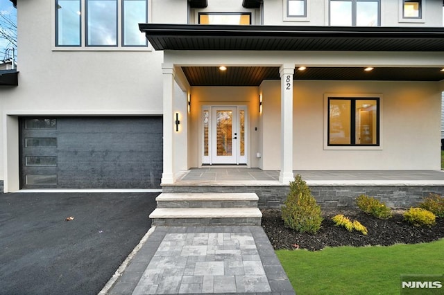 doorway to property with covered porch and a garage