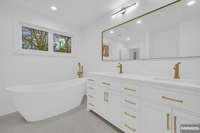 bathroom with tile patterned floors, a washtub, and vanity