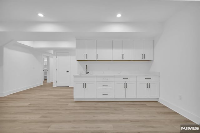 kitchen with light hardwood / wood-style floors, white cabinetry, and sink