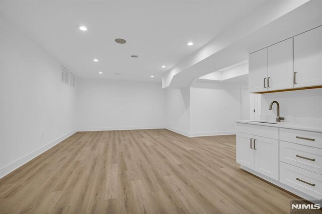 unfurnished living room with sink and light wood-type flooring