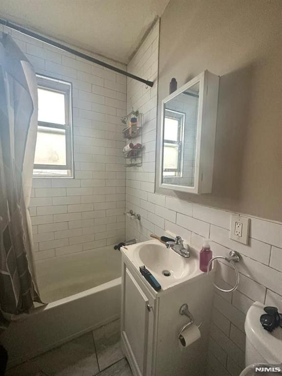 full bathroom with vanity, tile patterned flooring, toilet, shower / bath combo with shower curtain, and tile walls