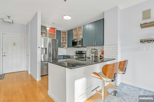 kitchen featuring blue cabinets, sink, a breakfast bar area, kitchen peninsula, and stainless steel appliances