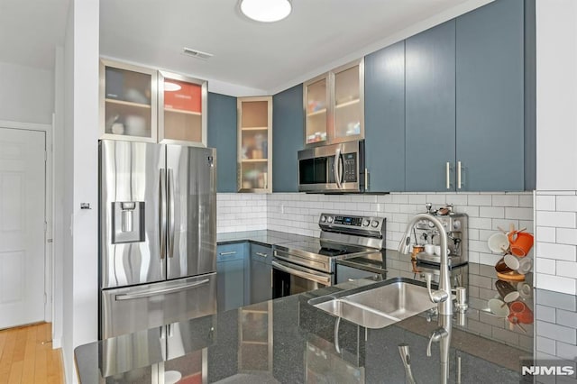 kitchen with appliances with stainless steel finishes, backsplash, blue cabinets, and sink