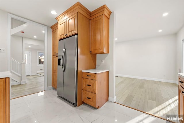 kitchen with stainless steel fridge with ice dispenser and light hardwood / wood-style floors