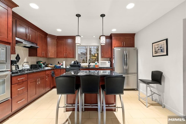 kitchen featuring a center island, hanging light fixtures, stainless steel appliances, a kitchen breakfast bar, and backsplash