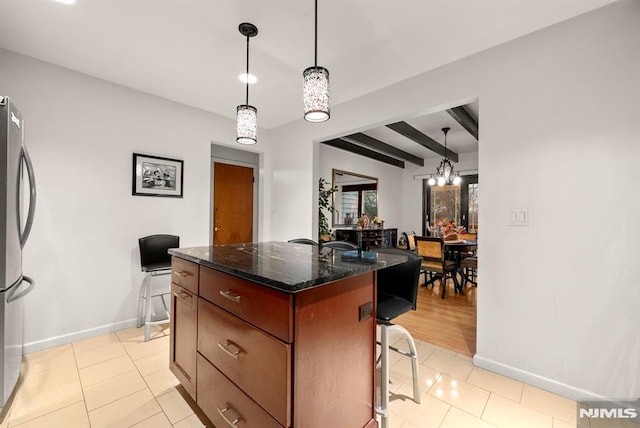 kitchen featuring a kitchen breakfast bar, stainless steel refrigerator, a center island, and decorative light fixtures