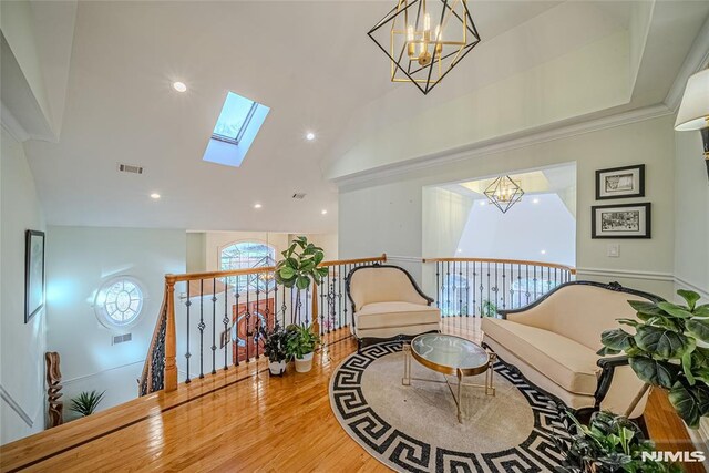 sitting room with vaulted ceiling with skylight, hardwood / wood-style flooring, and a chandelier